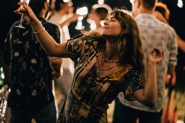 Group of people, men and women dancing together on party in back yard outdoors.